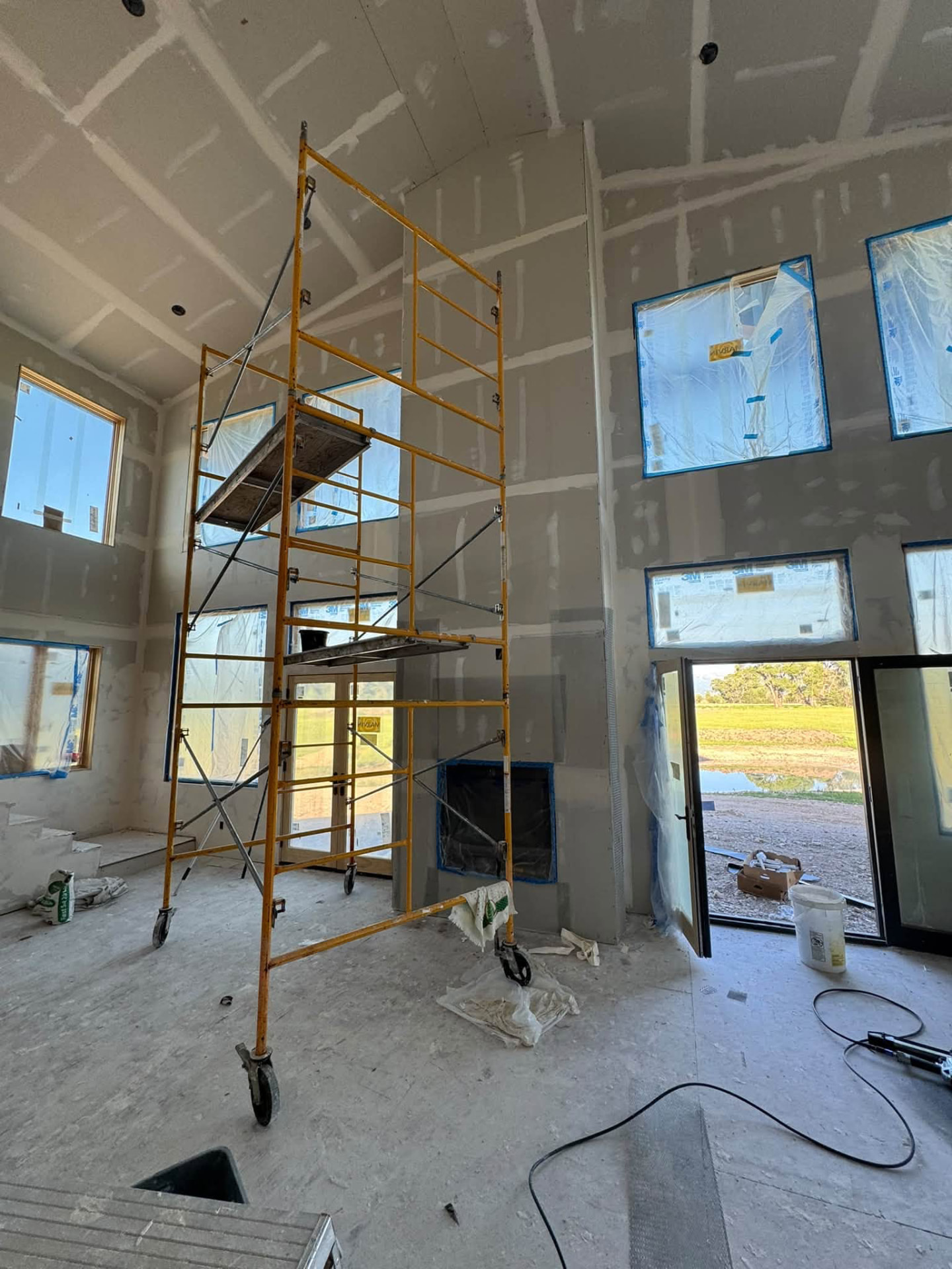 Scaffolding in a tall unfinished interior with exposed framing