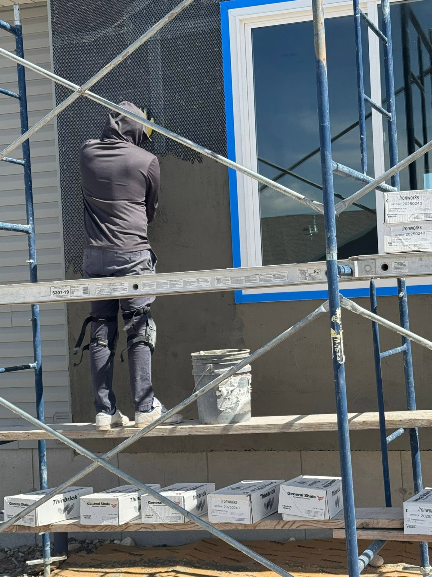 Mason preparing a wall with lath and mortar beside a window