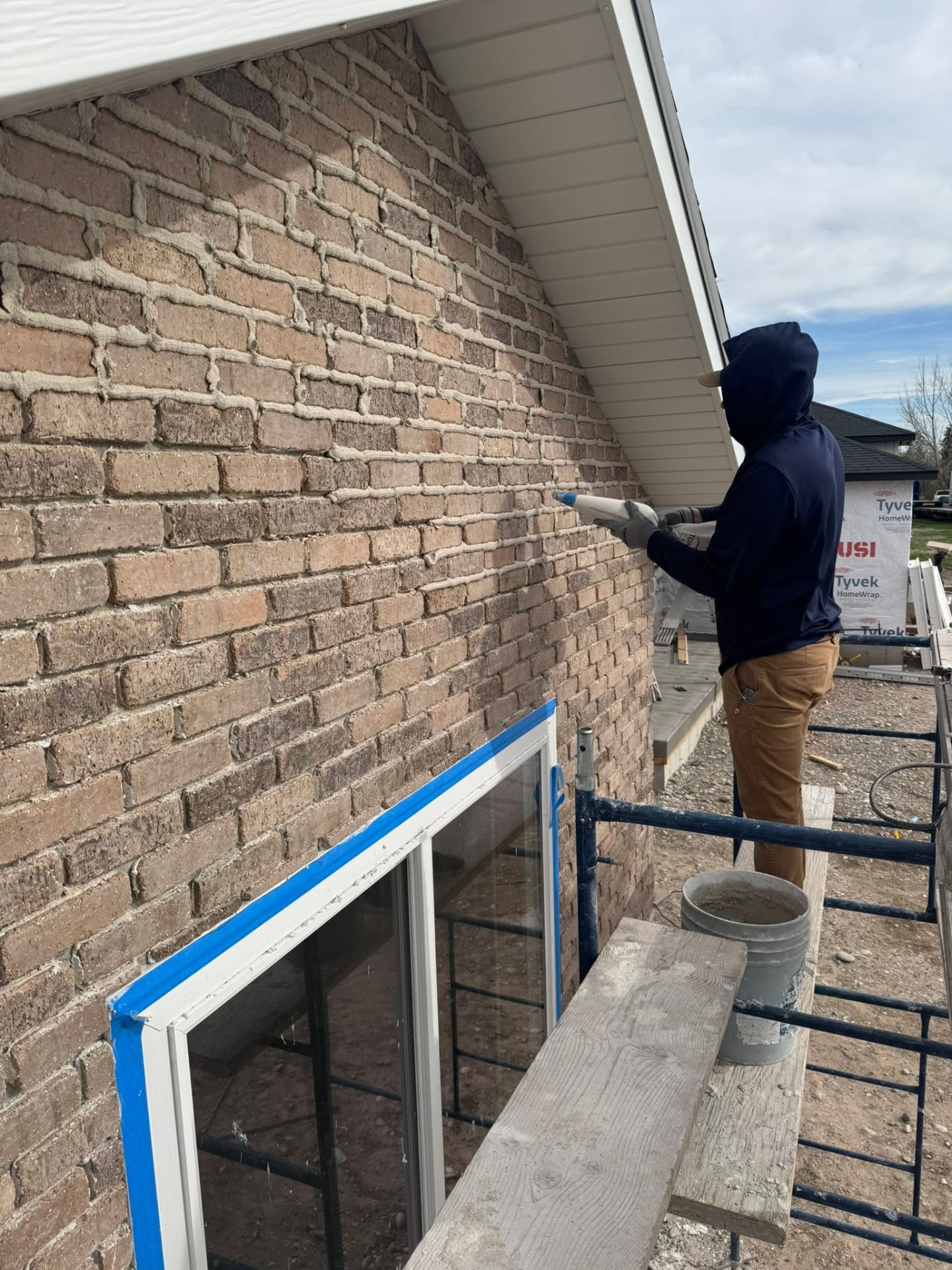 Mason working on a brick wall from scaffolding